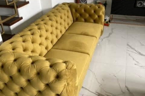 żółta pikowana sofa Cludo w welurowej tkaninie we wnętrzu